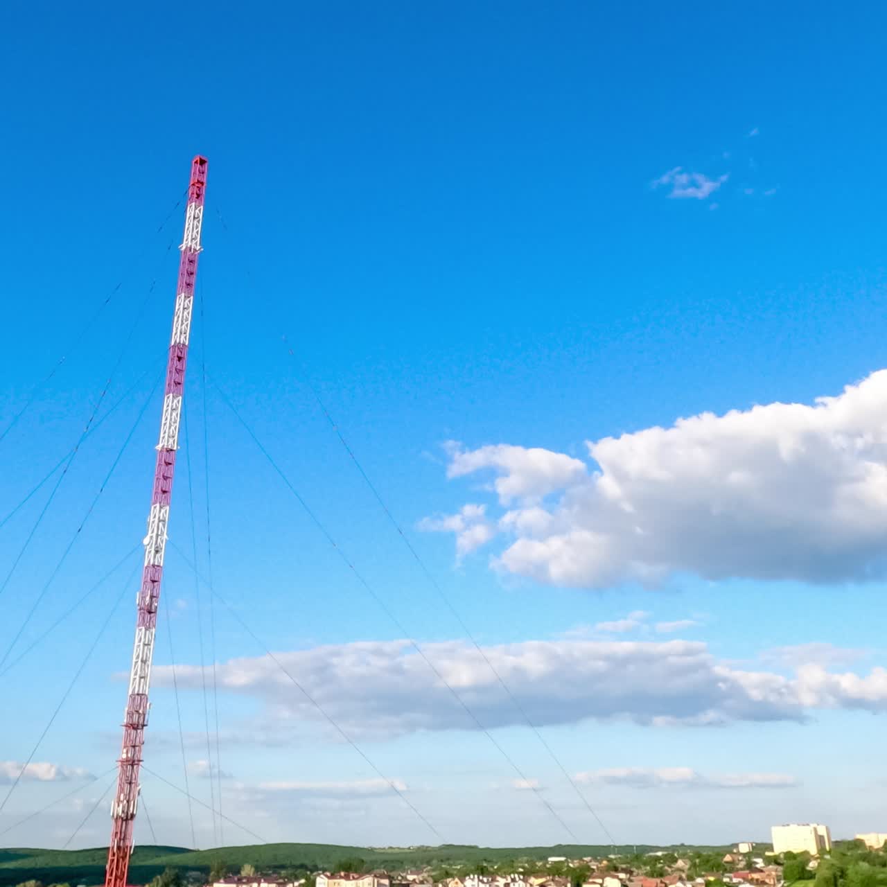 Little white clouds transforming in the clear blue sky. Amazing timelapse of the clouds over the city and television tower