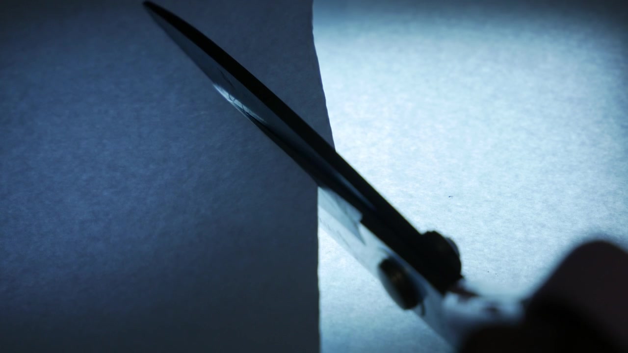 Silhouette of Hand Cutting Paper with Scissors