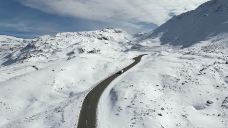 Camper-drive-Grossglockner-High-Alpine-Road-Mountain-Pass-in-Snow-covered-Austria-Alps---Aerial-4k