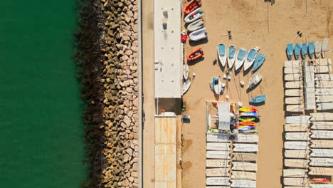una toma de arriba hacia abajo de un avión no tripulado capturando una playa llena de barcos por el mar verde