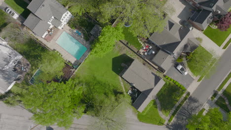 overhead view with scroll up of suburban neighborhood houses amongst trees in the spring