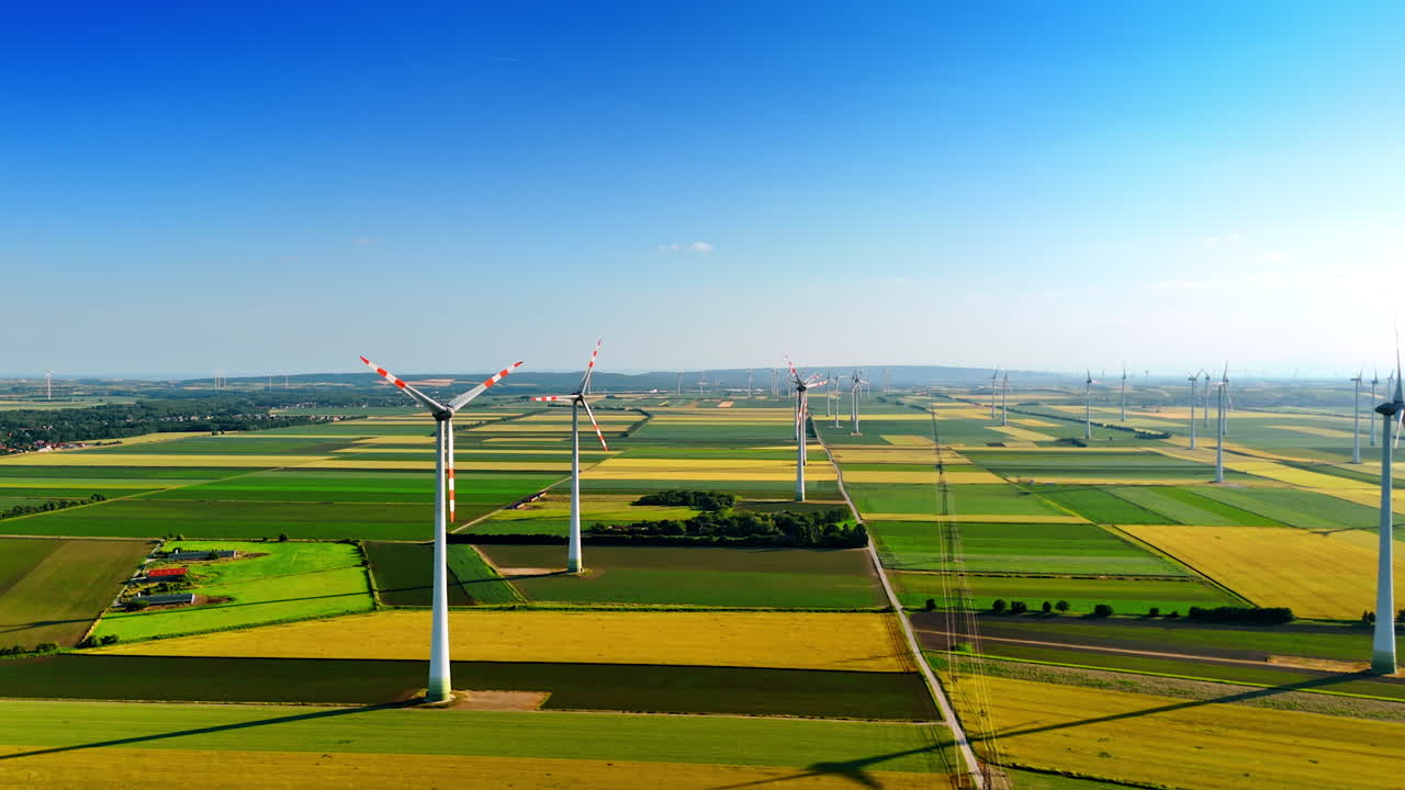 Wind turbines in fields. Wind turbines stand tall in vast green fields under a clear blue sky, showcasing renewable energy use in agriculture