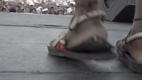 close-up of a person's feet wearing unique sandals on stage during a performance