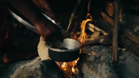 granos de café agregados al tazón de metal para asar a fuego abierto, uganda