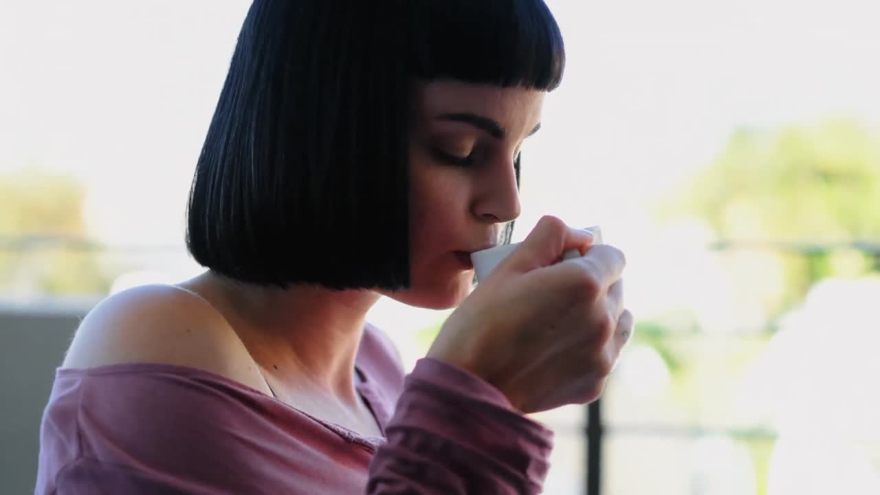 발코니 4k에서 책을 읽는 동안 커피를 마시는 여자