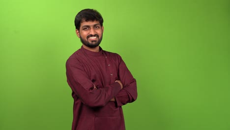 attractive young man watching towards camera with crossed arms, isolated green screen