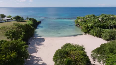 backward flyover tropical vegetation and white sand caleton beach in the dominican republic. panoramic aerial of beach bay with coral reefs