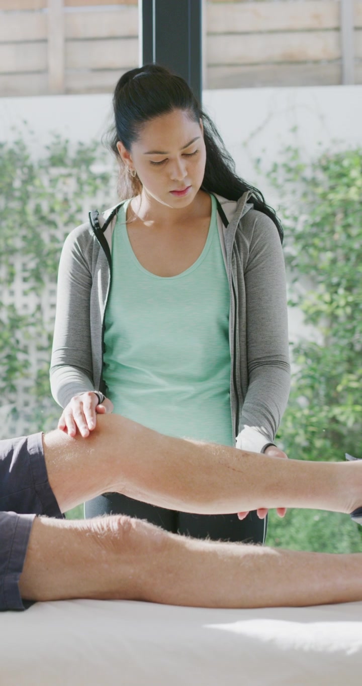Physical Therapist Examining Patient's Knee in Clinic