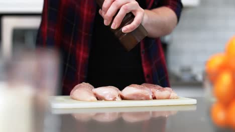 Man-sprinkling-black-pepper-on-meat-at-home-4k