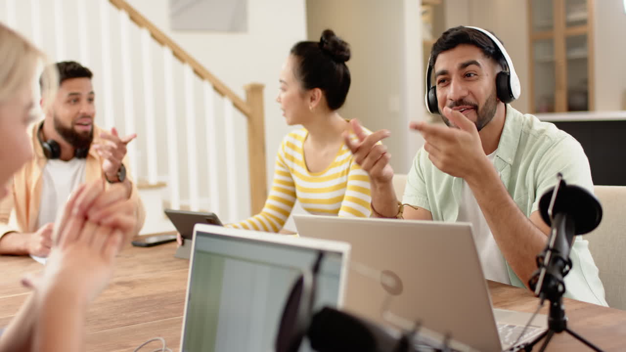 Collaborating on project, young diverse friends using laptops and tablets at home office