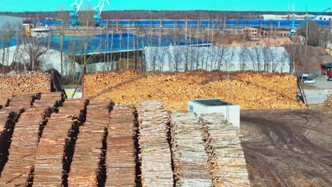 latvian timber processing facility: vast stockpiles of logs in brown and tan hues under a hazy, overcast sky, viewed from a high-angle with a wide-angle lens, showcasing industrial scale
