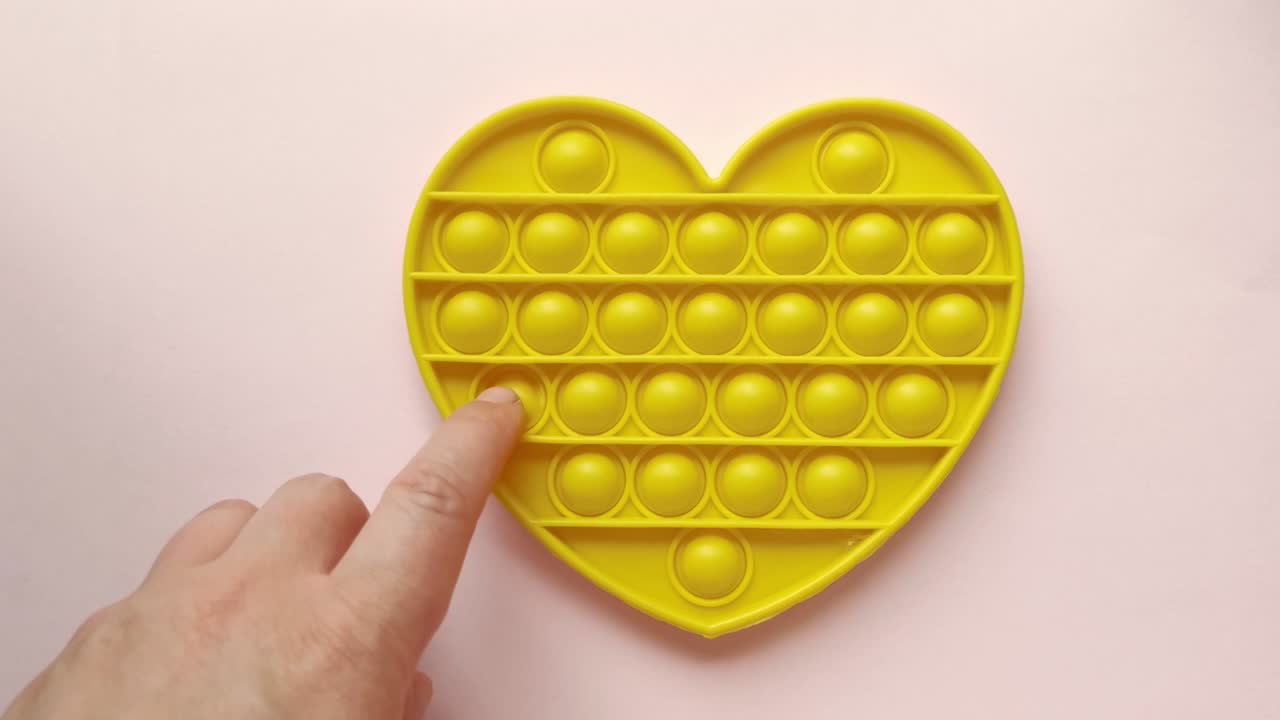 새로운 아기 장난감. 손가락 놀이. 재미있는 색. 성인 손 압축 둥근 실리콘. 형태 변경. 노란색 심장 모양