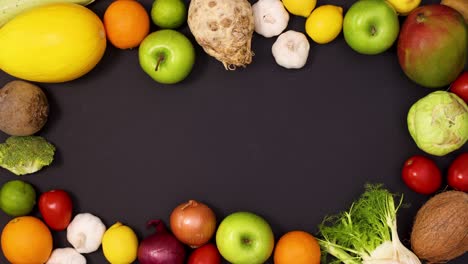 marco vibrante hecho de frutas y verduras frescas en movimiento sobre un fondo negro.