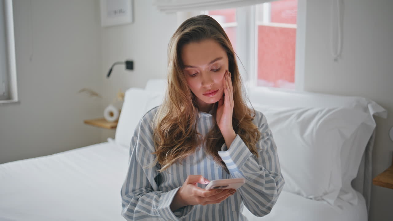 Depressed girl reading cellphone message in cozy bedroom closeup. Serious woman