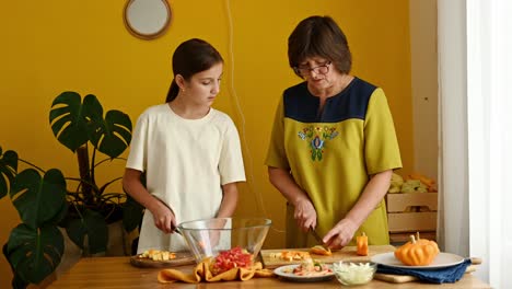 Mature-woman-teaching-granddaughter-to-chop-veggies