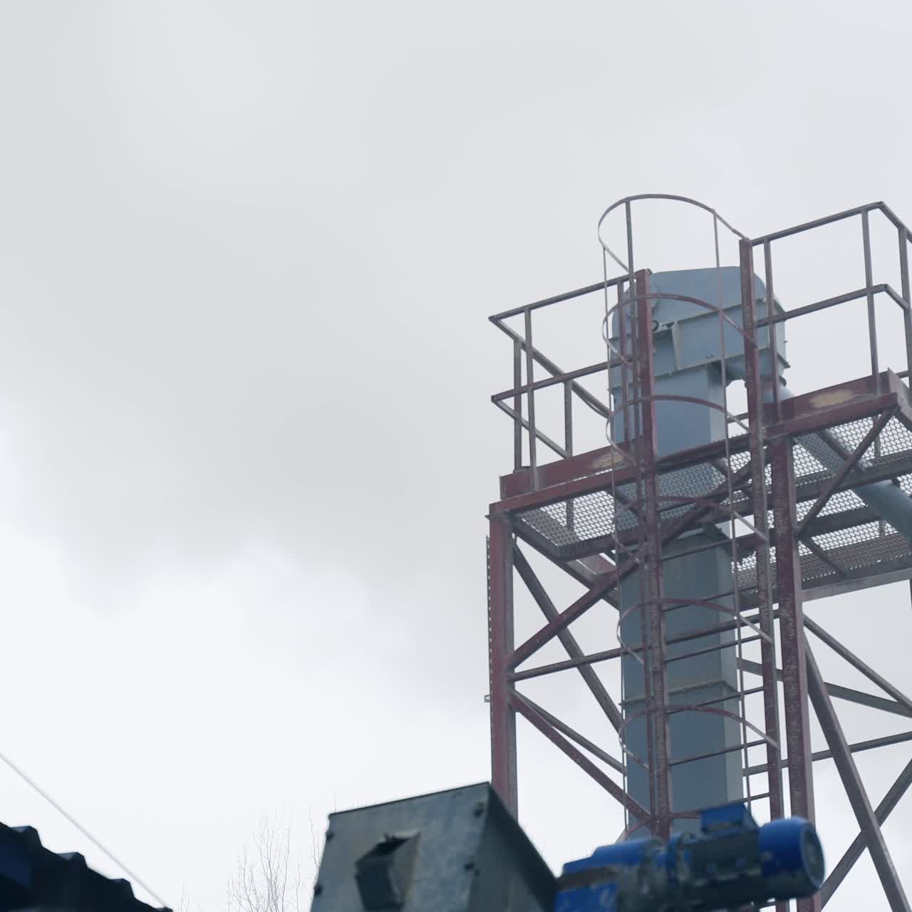 Thick smoke coming from behind the elevator premises into the air of industrial factory. Exterior of modern factory on processing grain crops