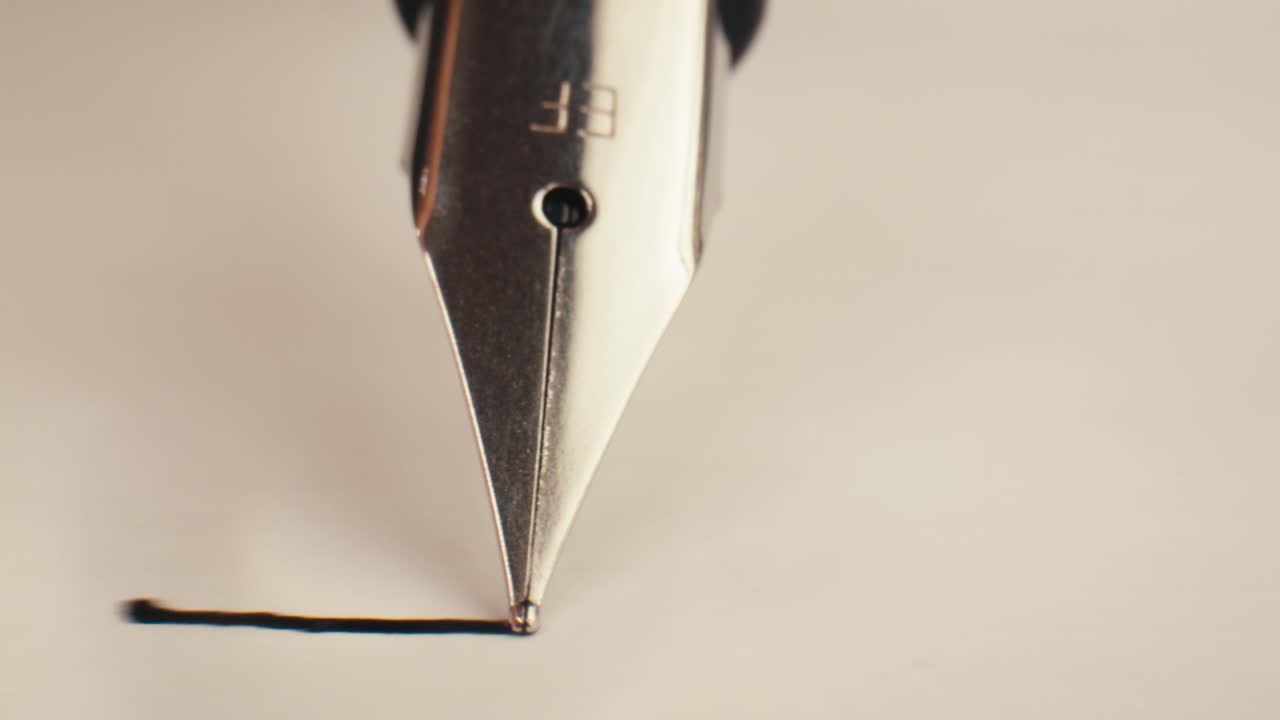 Primo piano del pennino di una penna stilografica che traccia una linea su carta