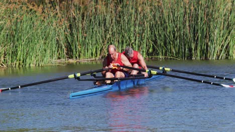 two senior caucasian men in rowing boat resting