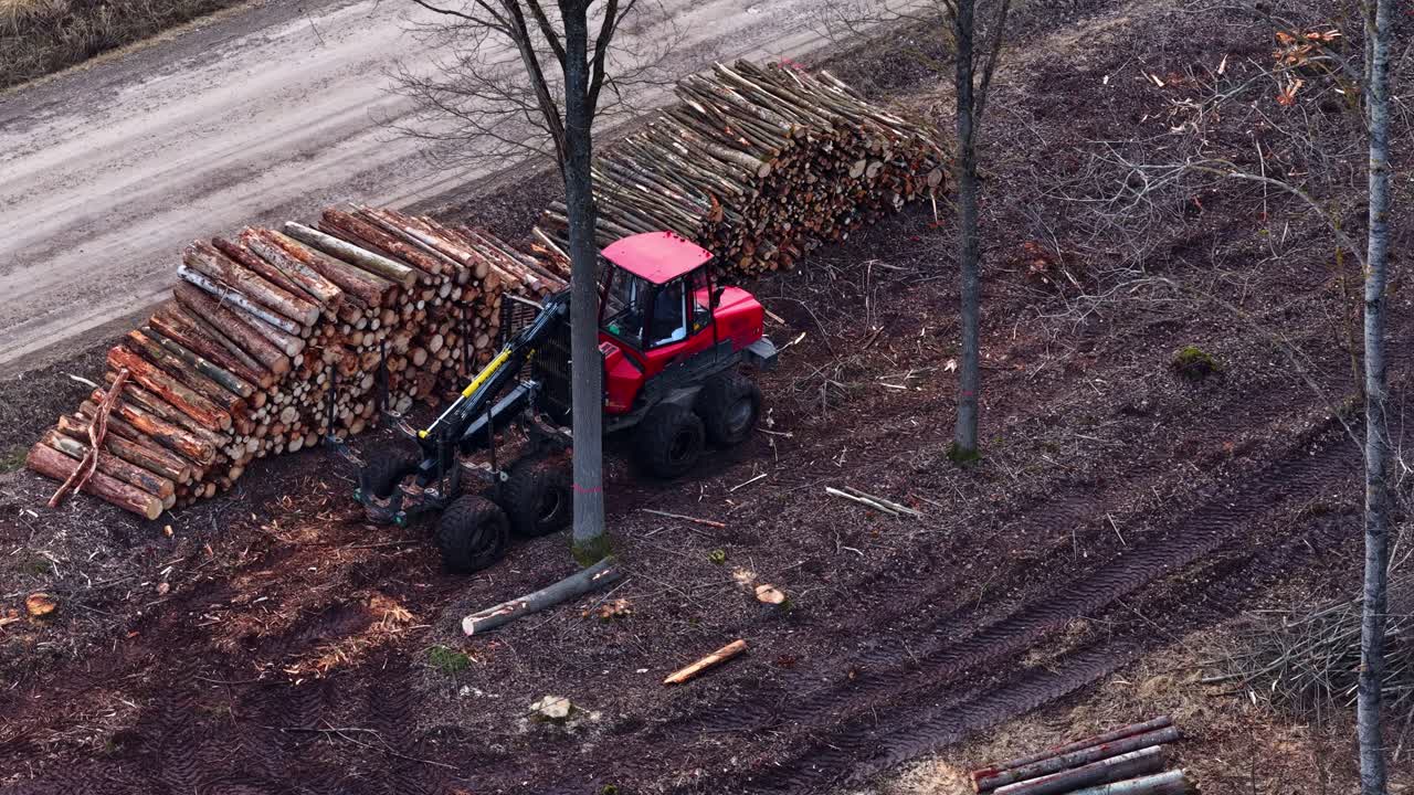 Forestry machine parked next to log pile for wood production and logging industry