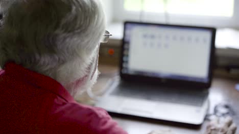 hombre mayor usando una computadora portátil sentado en la mesa en casa