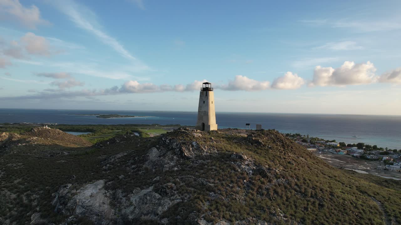 маяк на холме при заходе солнца, с видом на море и береговую линию, воздушный вид