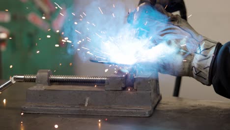 Close-up-of-man-mig-welding-bracket-on-a-vise-grip-slow-motion