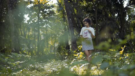 Slow-motion-shot-of-a-woman-in-a-white-and-rainbow-shirt-and-checkered-skirt-standing-in-a-forest