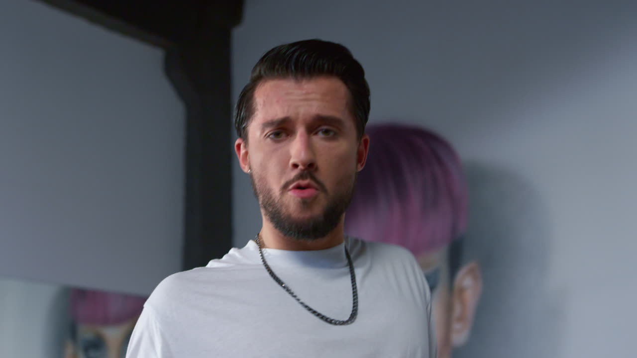 веселый танцор смотрит на камеру в современной студии. красивый мужчина танцует в помещении.