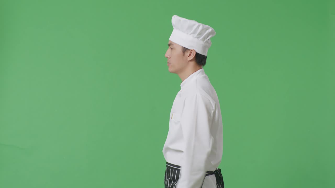 Vista laterale di uno chef asiatico che cammina nello studio con sfondo green screen