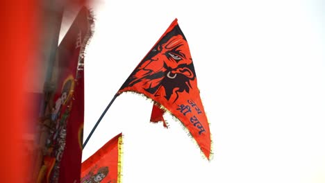 orange color flags with lord hanuman face on it depicting santana dharma and hinduism waving in air at ayodhya , uttar pradesh , india