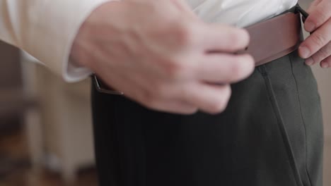 groom wears belt, man in white shirt puts belt on pants in wedding morning, businessman preparation