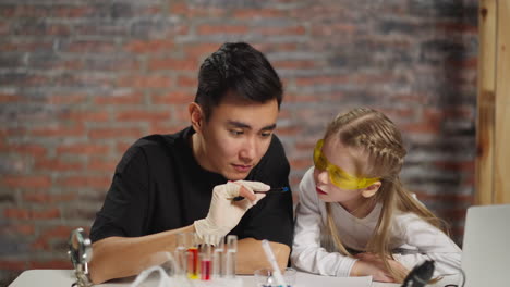 asian scientist and little student look at crystal in lab