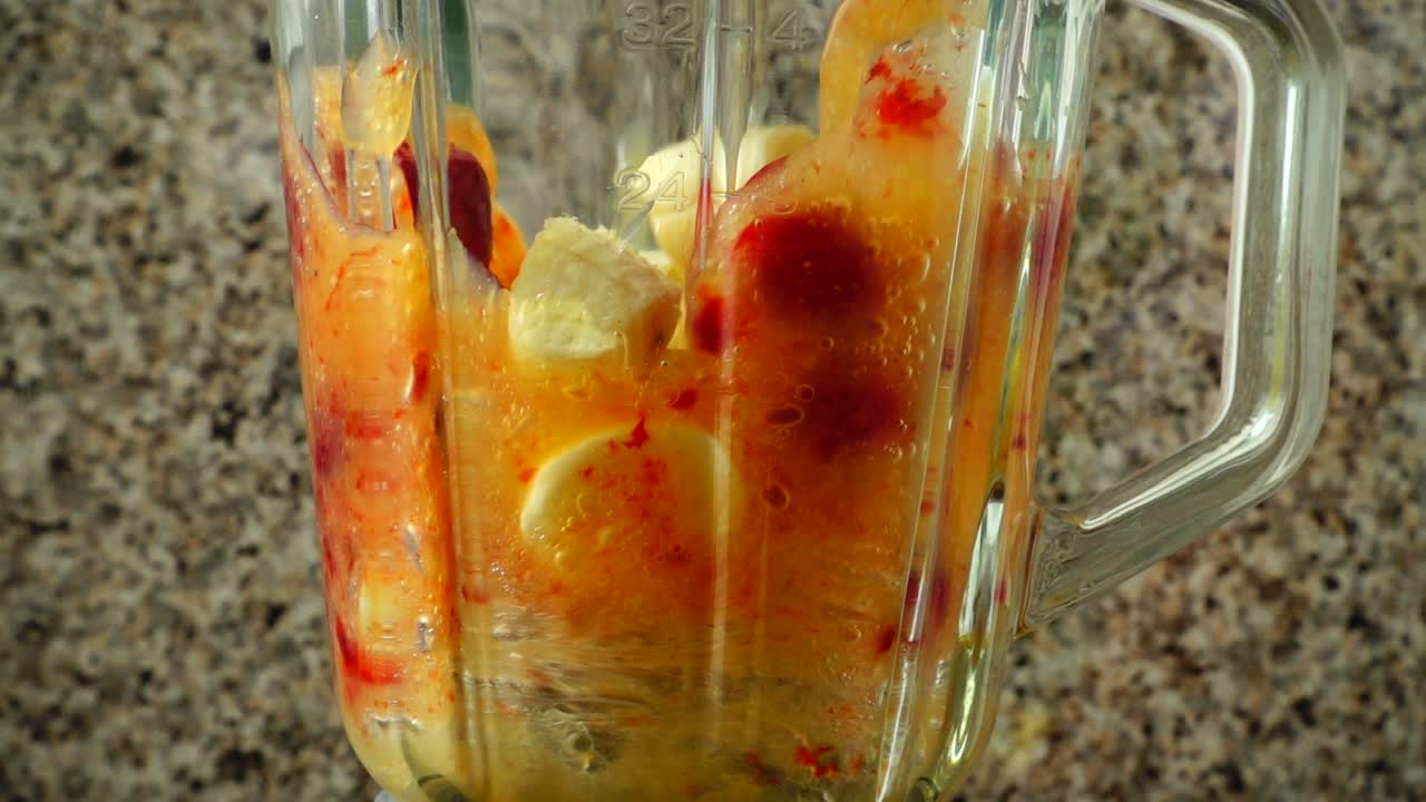 Preparazione di un cocktail con fragole, banane e succo d'arancia nel frullatore. Rallentatore.