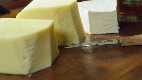 Narrow-focus-close-up:-Knife-cuts-slice-off-wedge-of-Brie-cheese