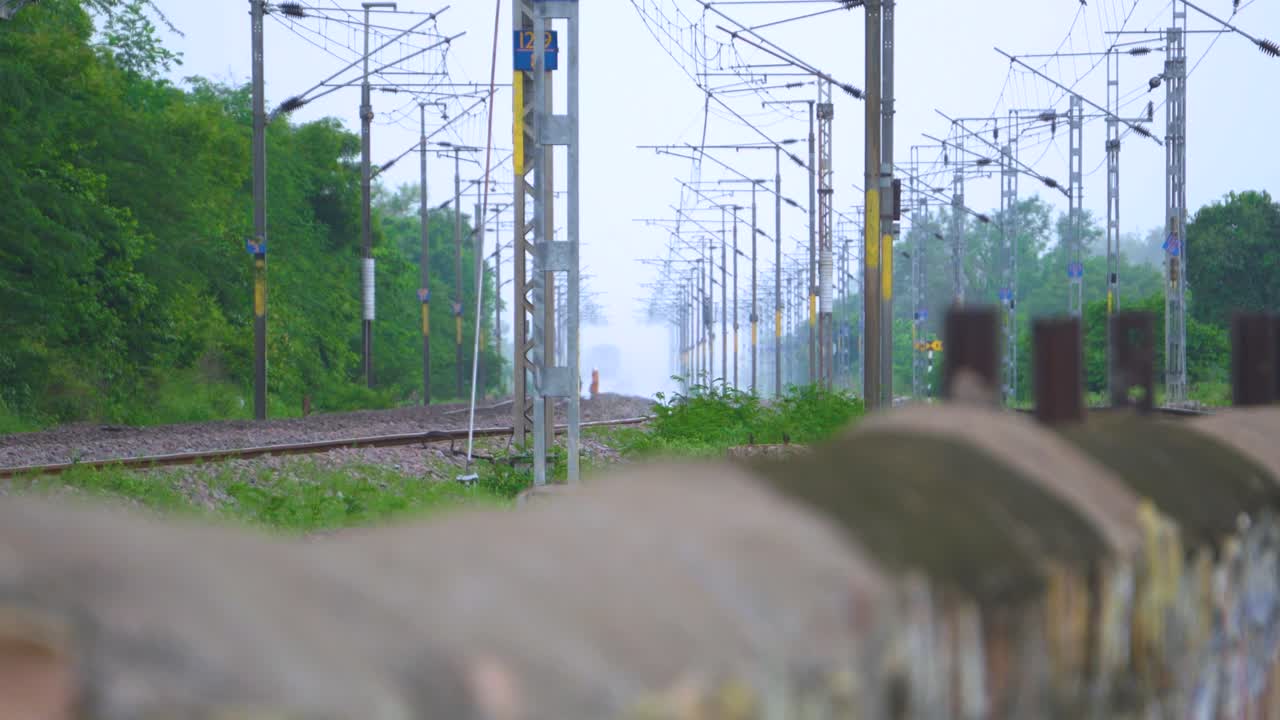 인도 에서 사람 들 이 위 에 전선 이 있는 철도 트랙 을 위험 하게 건너고 있다