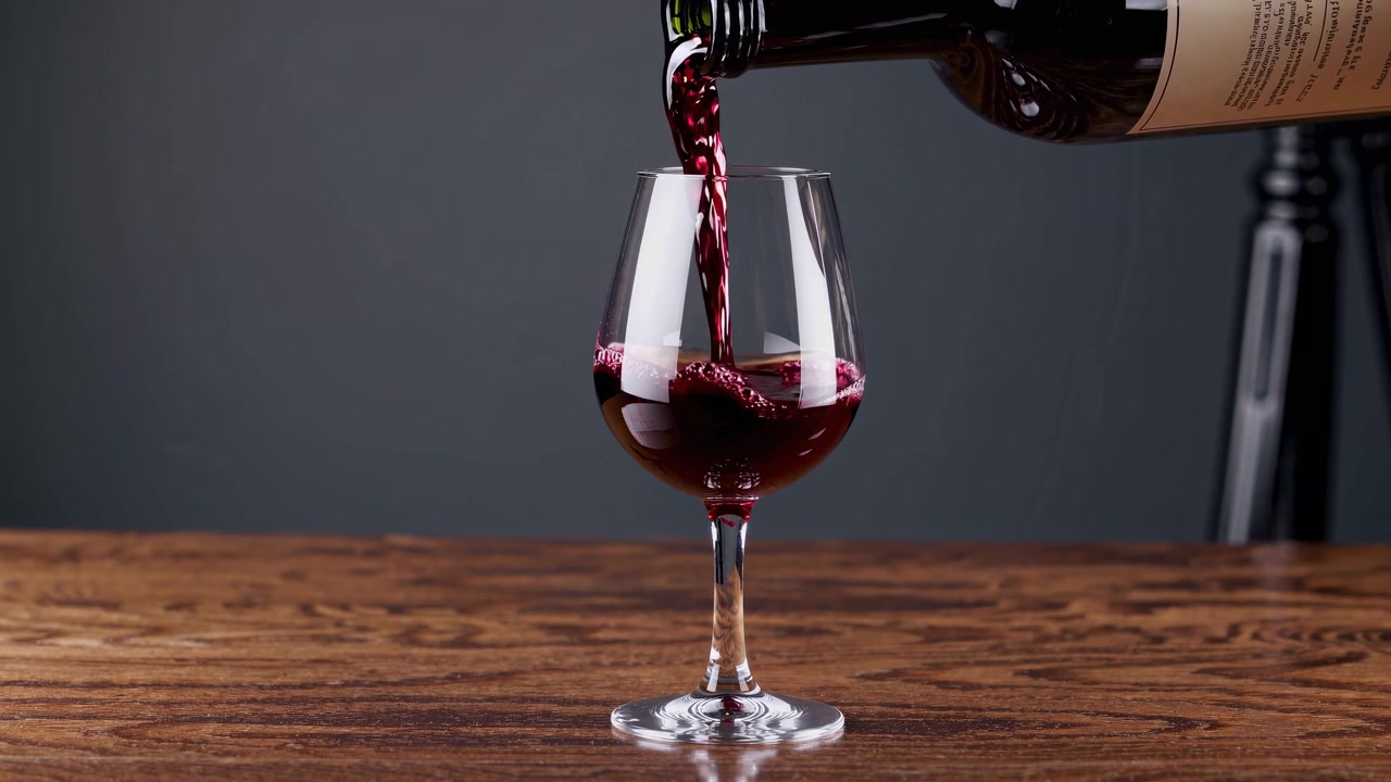Vino rosso versato dalla bottiglia in un bicchiere