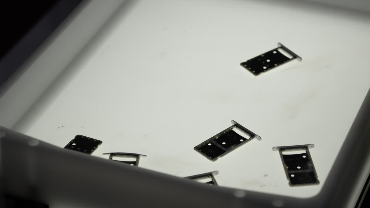 Multiple SIM Card Trays Falling and Settling on a White Background