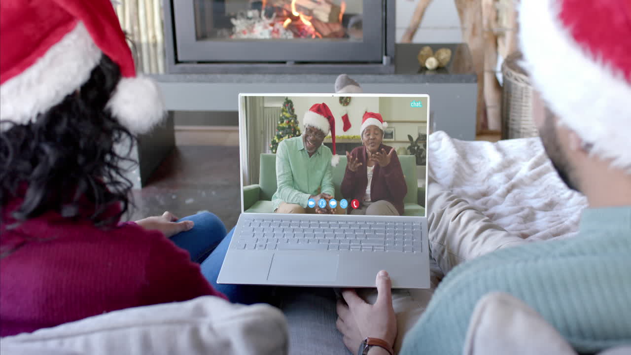 Coppia felice e multietnica e genitori anziani che fanno una videochiamata di Natale via laptop, al rallentatore.