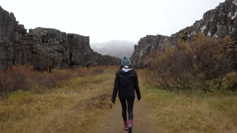 mujer joven caminando en un cañón islandés - ancho