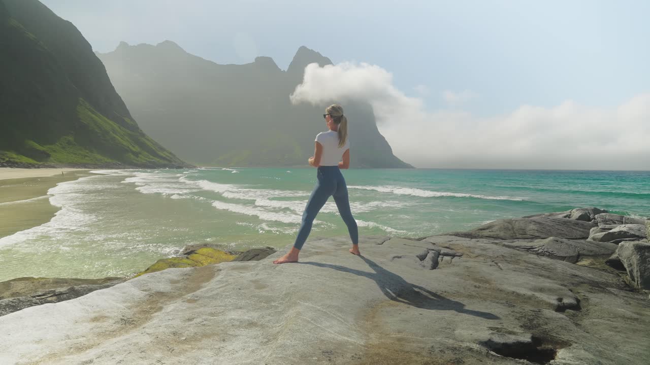 postura de guerrero de yoga realizada por una mujer atractiva en la costa de noruega