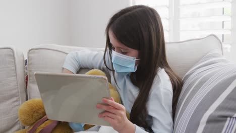 girl wearing face mask using digital tablet at home