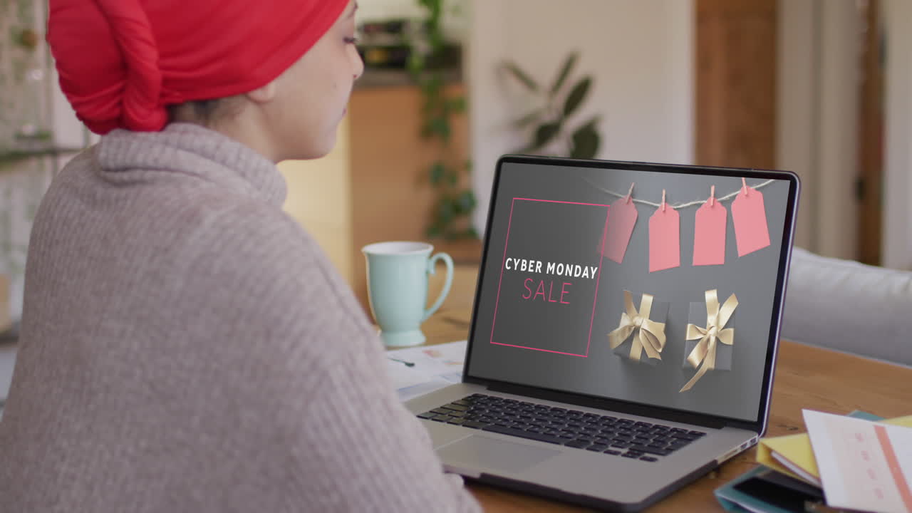 Biracial woman at table using laptop, online shopping on cyber monday, slow motion