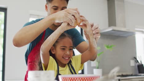 Happy-biracial-father-and-daughter-baking-together-in-kitchen