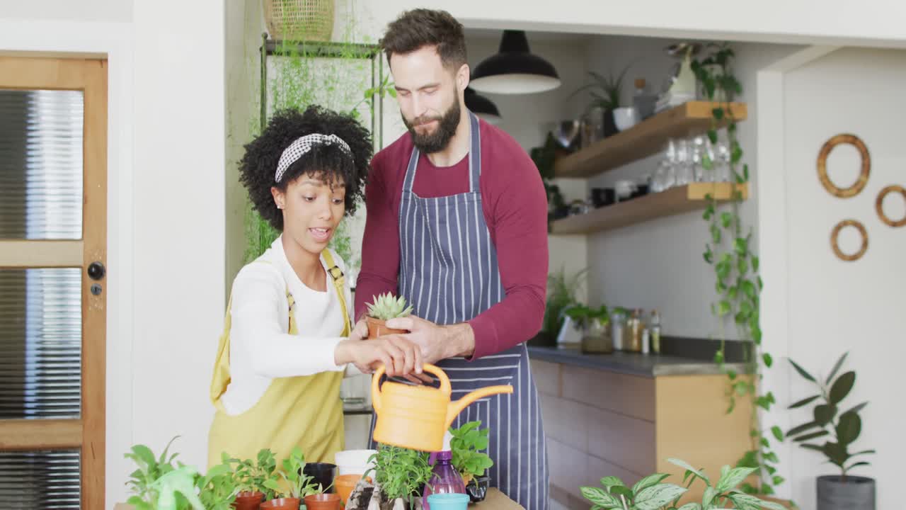 video de una feliz pareja diversa cuidando las plantas en casa, con espacio para copiar