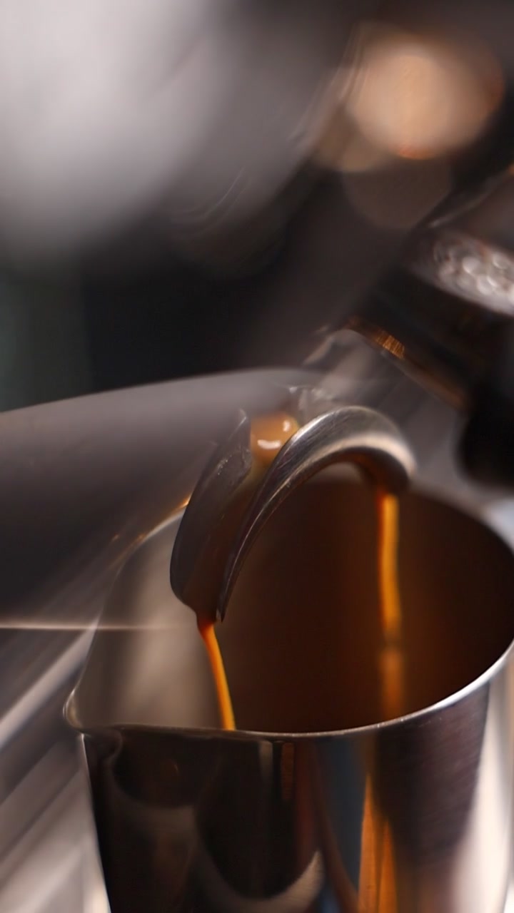 Caffè espresso fresco che si versa dal portafiltro in una lattiera metallica