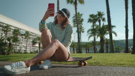 woman taking selfie on skateboard in park