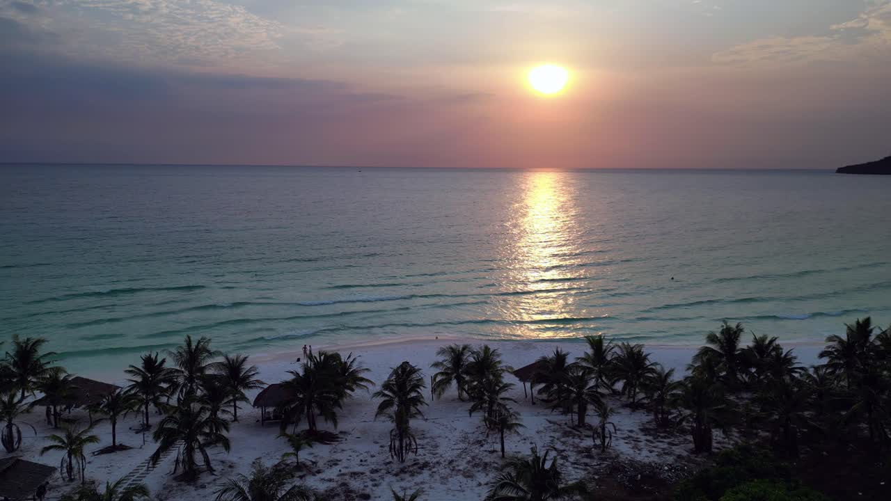Sok San Beach at sunset, with palm trees, white sand and calm turquoise water in Koh Rong island, Cambodia. Great aerial view flight panorama overview drone