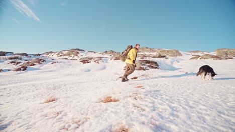 Junger-Mann-Mit-Rucksack-Und-Alaskischer-Malamute-hund-Klettern-An-Einem-Sonnigen-Wintertag-In-Norwegen-Auf-Den-Schneebedeckten-Berg