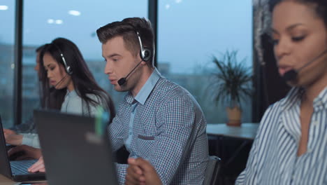 customer service representatives working in an office with headsets and laptops