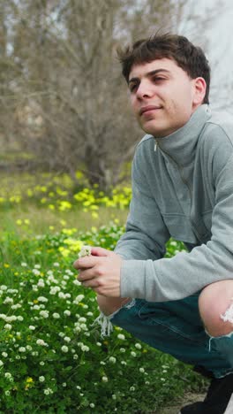 Man Picking And Smelling A White Flower From The Ground